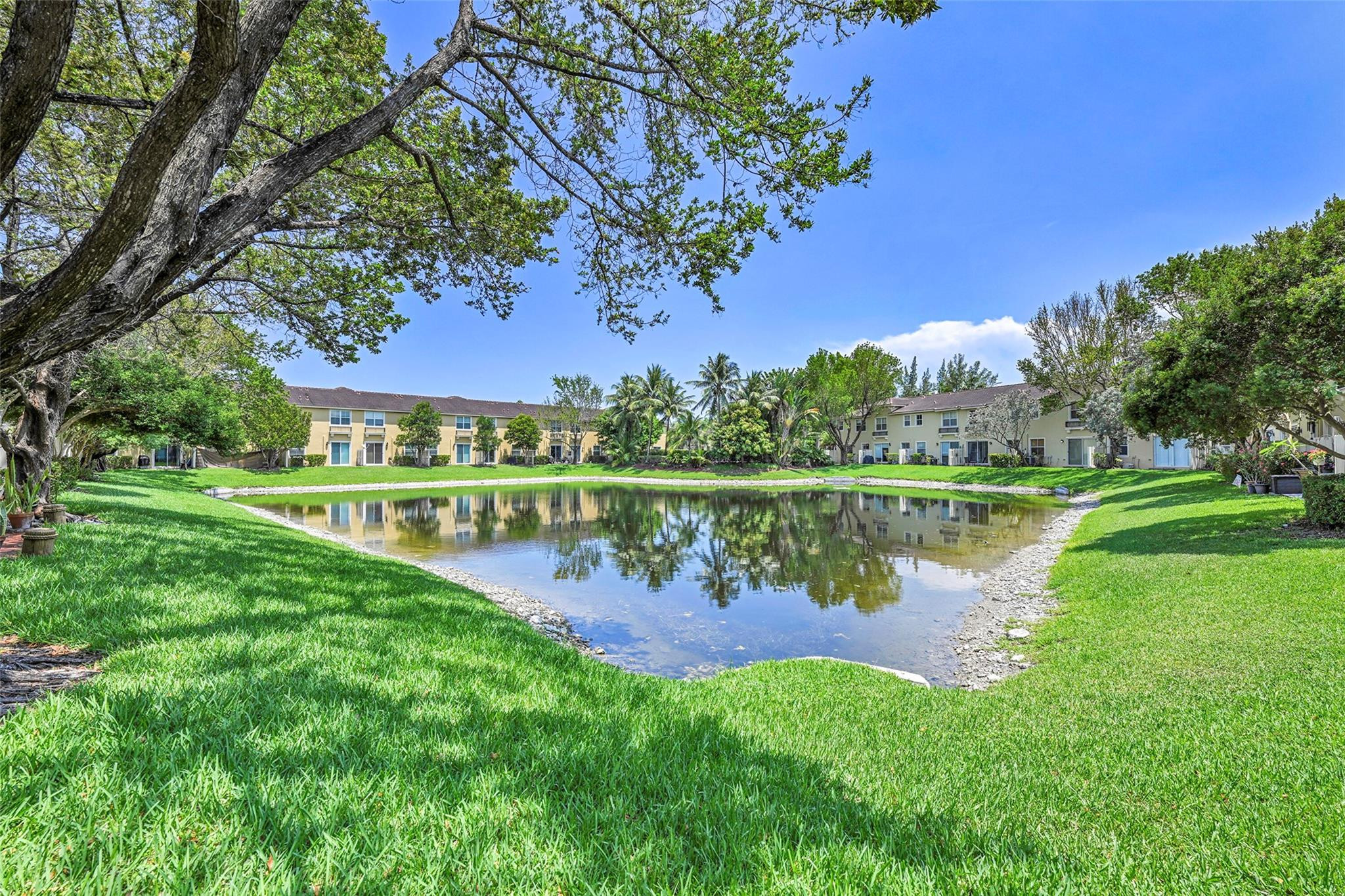2851 Prospect Road, Unit 1202 Tamarac, FL 33309 - Photo 3 of 25 a view of a lake with a yard and large trees