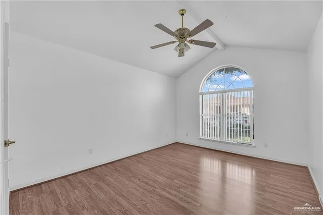 an empty room with wooden floor chandelier fan and windows