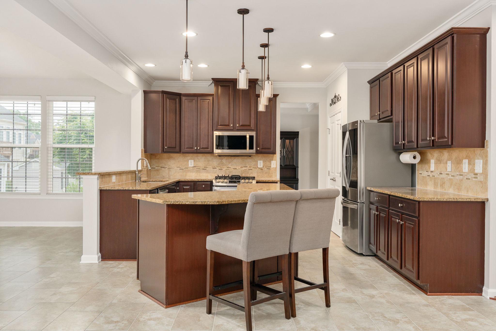 9417 Reservoir Road Fredericksburg, VA 22407 - Photo 26 of 76 a kitchen with kitchen island granite countertop wooden cabinets and a refrigerator