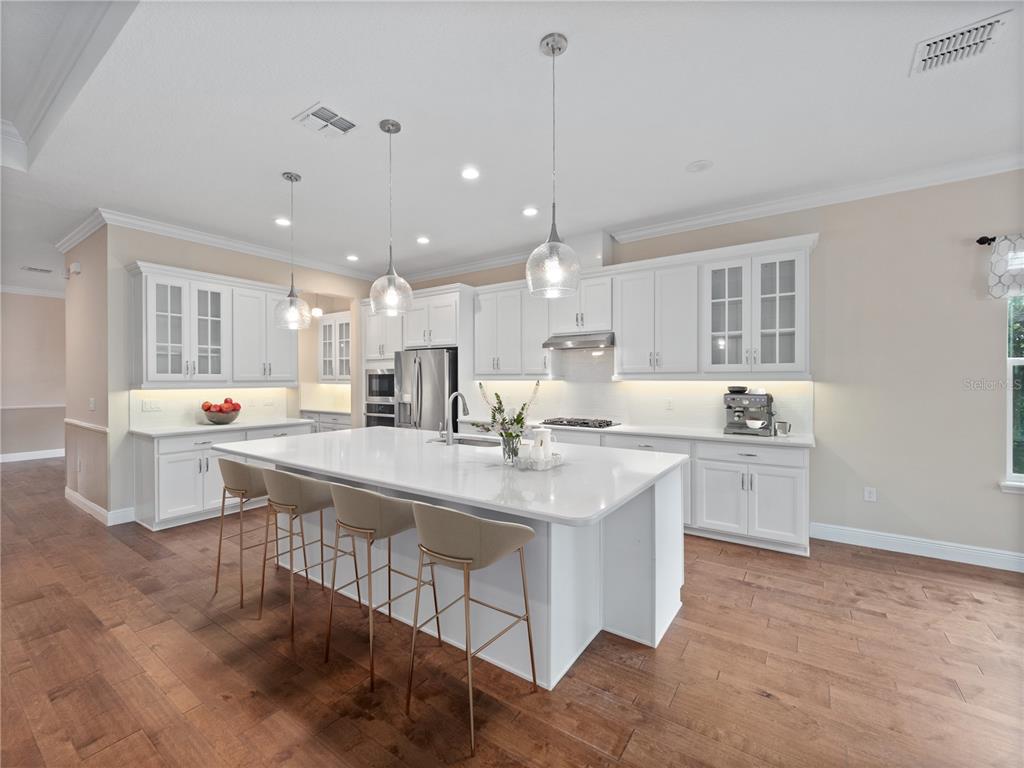 2922 Reef Knot Place Winter Park, FL 32792 - Photo 11 of 49 a large kitchen with kitchen island a sink white cabinets and wooden floor
