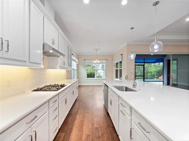 a large kitchen with stainless steel appliances kitchen island a large counter top a stove and a chandelier