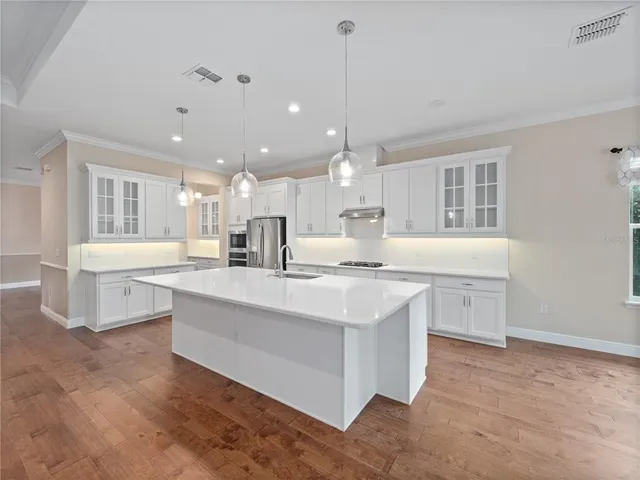 a kitchen with stainless steel appliances granite countertop a refrigerator a sink dishwasher a stove and a refrigerator with wooden floor