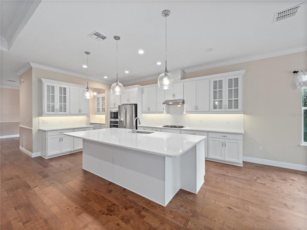 2922 Reef Knot Place Winter Park, FL 32792 - Photo 15 of 49 a large white kitchen with kitchen island a sink a stove a dining table and chairs