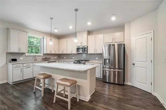 a kitchen with kitchen island white cabinets and stainless steel appliances