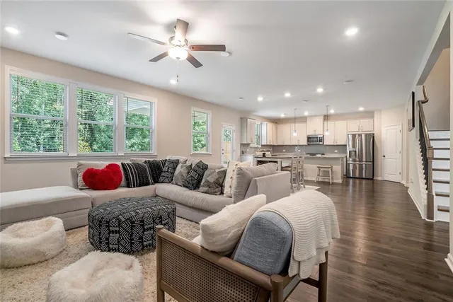 a living room with furniture kitchen view and a large window