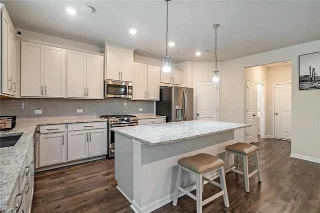 a open kitchen with stainless steel appliances granite countertop a stove a refrigerator a oven a sink with a dining table and chairs