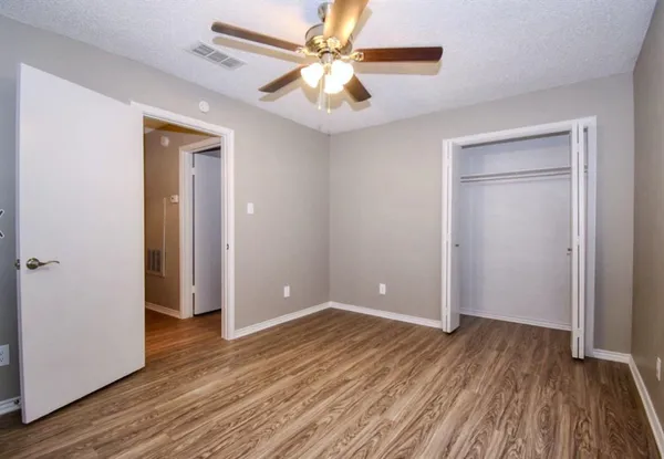 an empty room with wooden floor and a ceiling fan