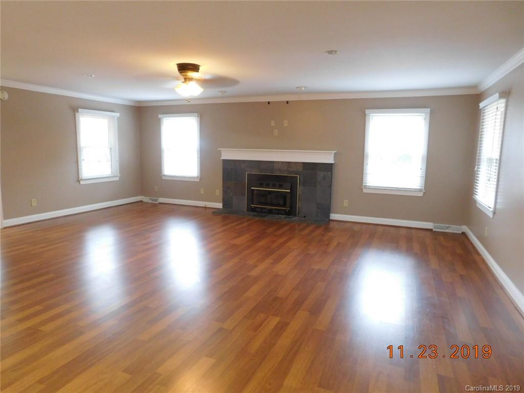 4020 Sincerity Road Monroe, NC 28110 - Photo 7 of 23 an empty room with wooden floor fireplace and windows