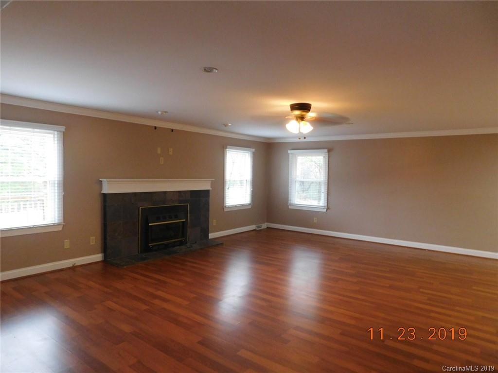 4020 Sincerity Road Monroe, NC 28110 - Photo 8 of 23 an empty room with wooden floor fireplace and windows
