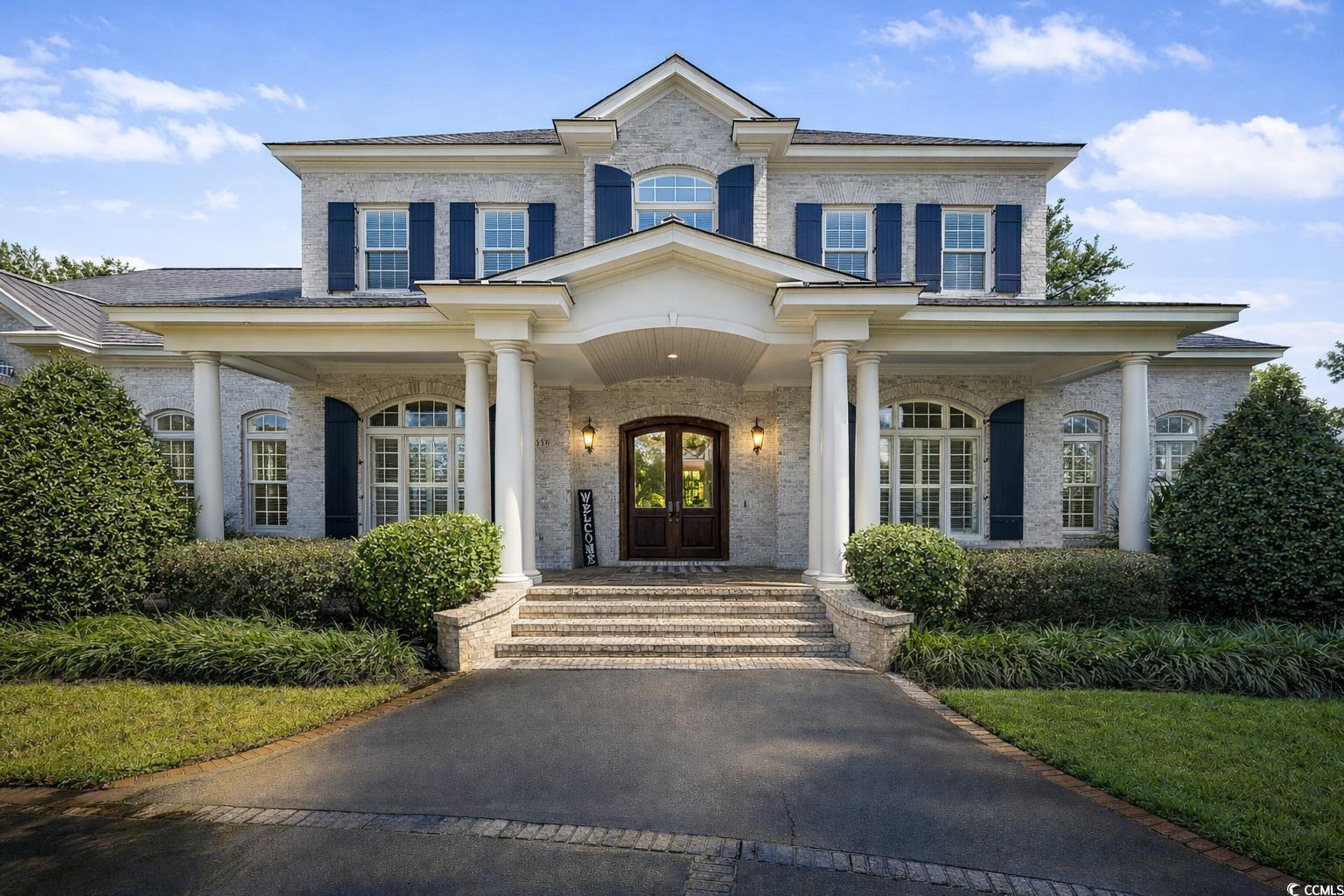 View of front facade featuring covered porch, french doors, and brick siding