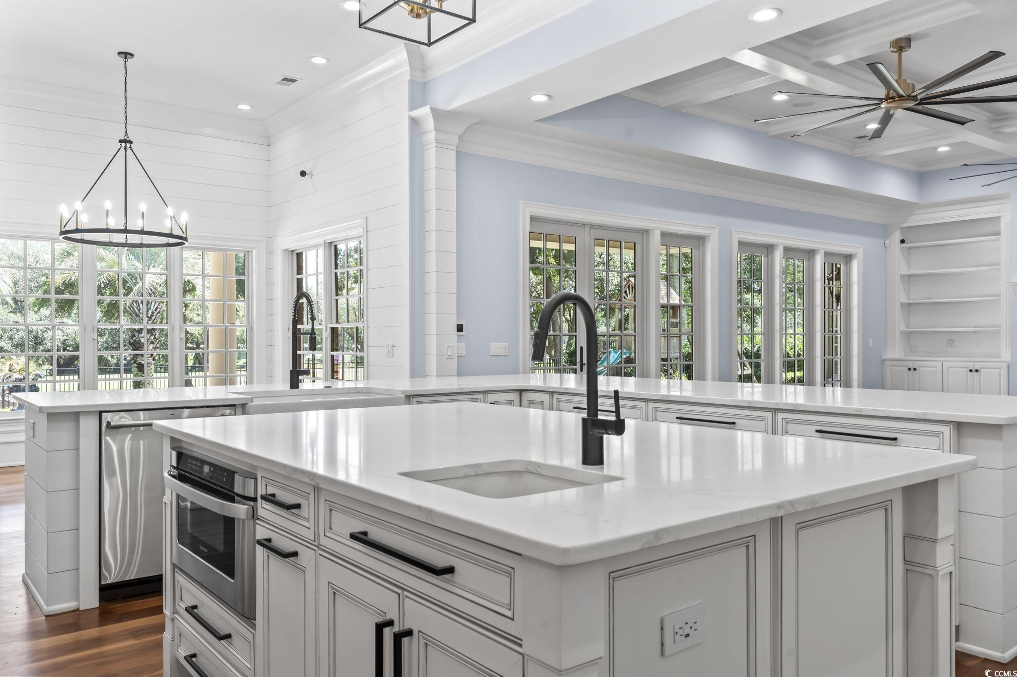 9318 Cove Drive Myrtle Beach, SC 29572 - Photo 12 of 40 Kitchen with a chandelier, light stone counters, dark wood-type flooring, pendant lighting, and ornamental molding
