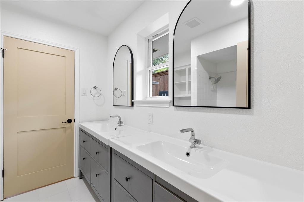 4446 Thunder Road Dallas, TX 75244 - Photo 20 of 30 Double vanity with integrated white sinks, gray cabinetry, and two arched mirrors