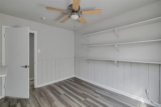 a view of empty room with wooden floor and fan