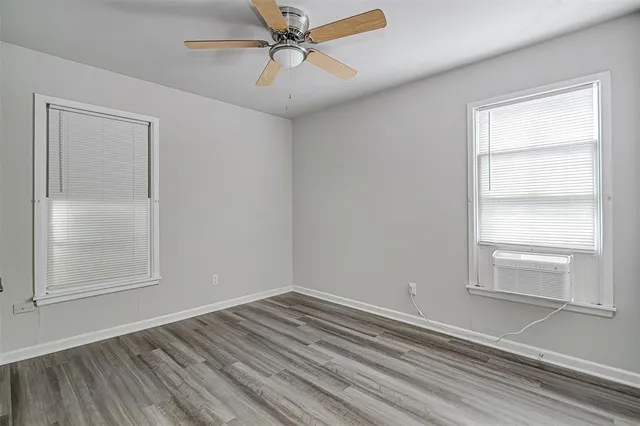 a view of empty room with wooden floor and fan