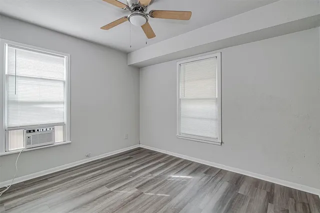 an empty room with a window and a ceiling fan