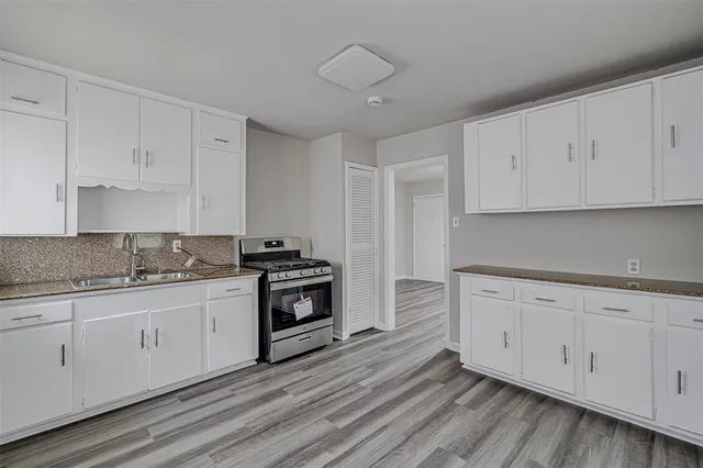 a kitchen with granite countertop white cabinets and stainless steel appliances
