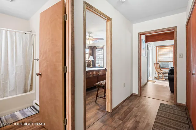 a view of a hallway with wooden floor and a bedroom