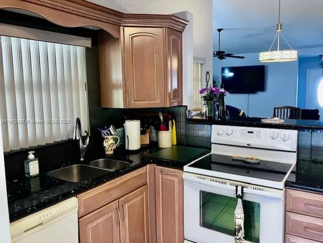 a kitchen with granite countertop a sink stainless steel appliances a counter top space and cabinets
