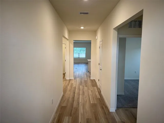 a view of a hallway with wooden floor and a bathroom