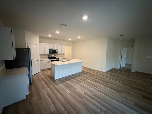 a kitchen with stainless steel appliances kitchen island granite countertop a stove a sink and a refrigerator