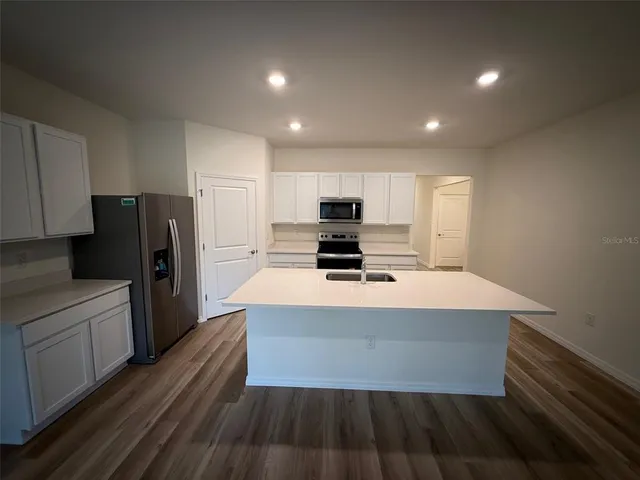 a large kitchen with stainless steel appliances a refrigerator and a stove top oven