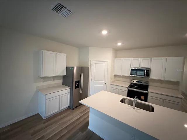 a kitchen with refrigerator cabinets and wooden floor