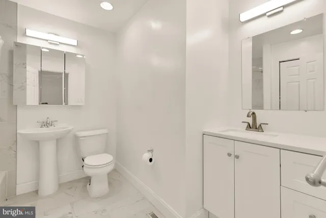 a bathroom with a toilet a sink a mirror and vanity