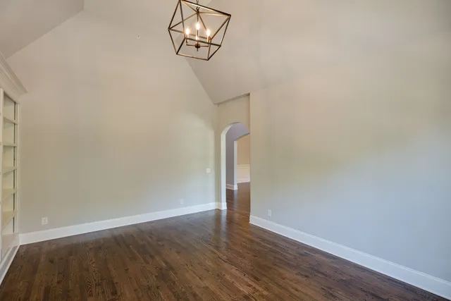 a view of an empty room with wooden floor fireplace and a window