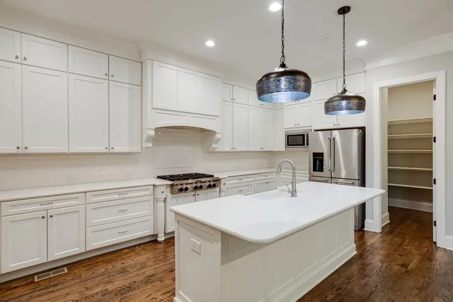 a kitchen with a sink chandelier and wooden floor