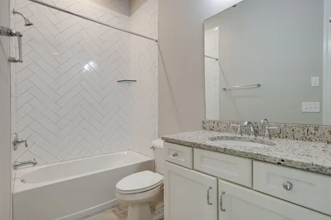 a bathroom with a granite countertop toilet a sink and a mirror