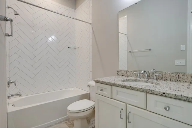 a bathroom with a granite countertop toilet a sink and a mirror