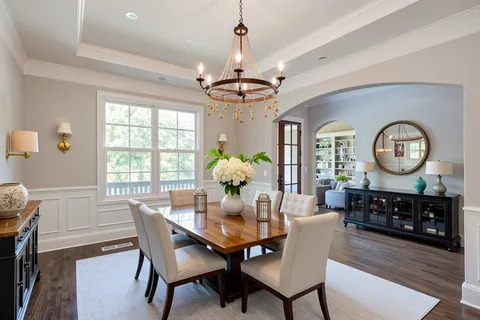an empty room with wooden floor chandelier and windows
