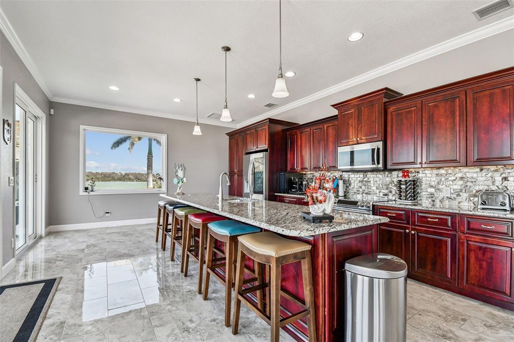 582 Johns Pass Avenue Madeira Beach, FL 33708 - Photo 21 of 100 a large kitchen with stainless steel appliances granite countertop a stove a sink a oven and a wooden cabinets