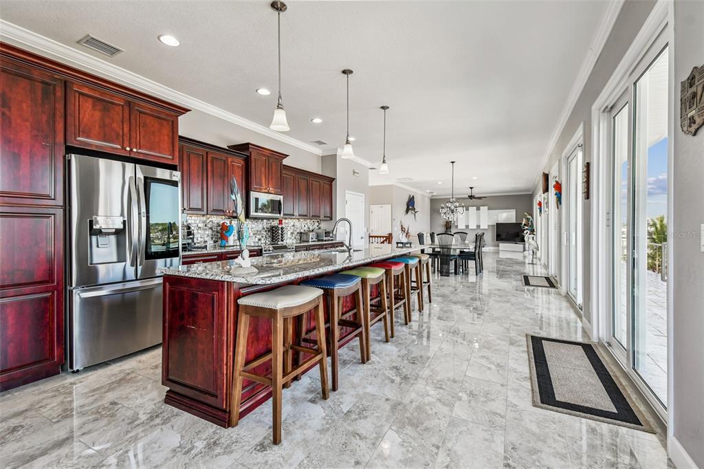 582 Johns Pass Avenue Madeira Beach, FL 33708 - Photo 22 of 100 a kitchen with stainless steel appliances granite countertop a stove top oven a refrigerator a sink and a dining table with granite countertop