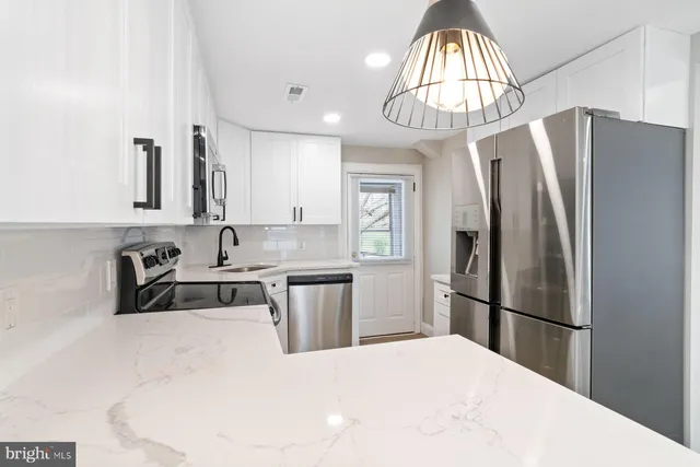 a kitchen with stainless steel appliances a refrigerator a sink a stove and white cabinets