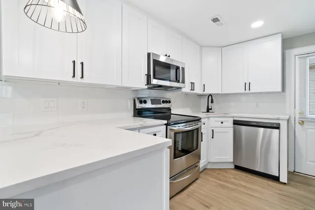 a kitchen with stainless steel appliances a sink dishwasher a stove and a refrigerator