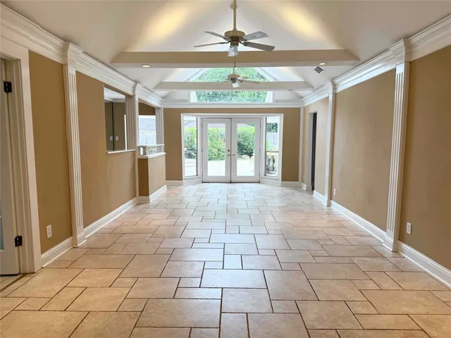 an empty room with wooden floor and way to kitchen