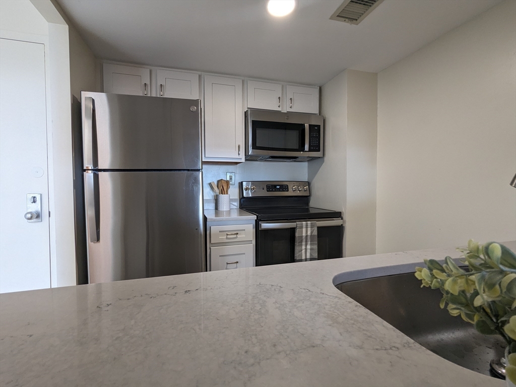 750 Davol Street, Unit 1214 Fall River, MA 02720 - Photo 7 of 42 a kitchen with stainless steel appliances a refrigerator microwave stove and sink