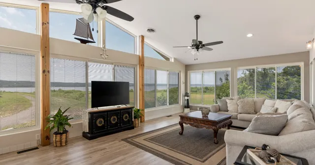 a living room with furniture a floor to ceiling window and a flat screen tv