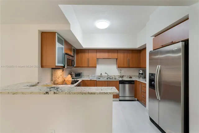 a kitchen with stainless steel appliances granite countertop a refrigerator a stove and a sink with wooden floor