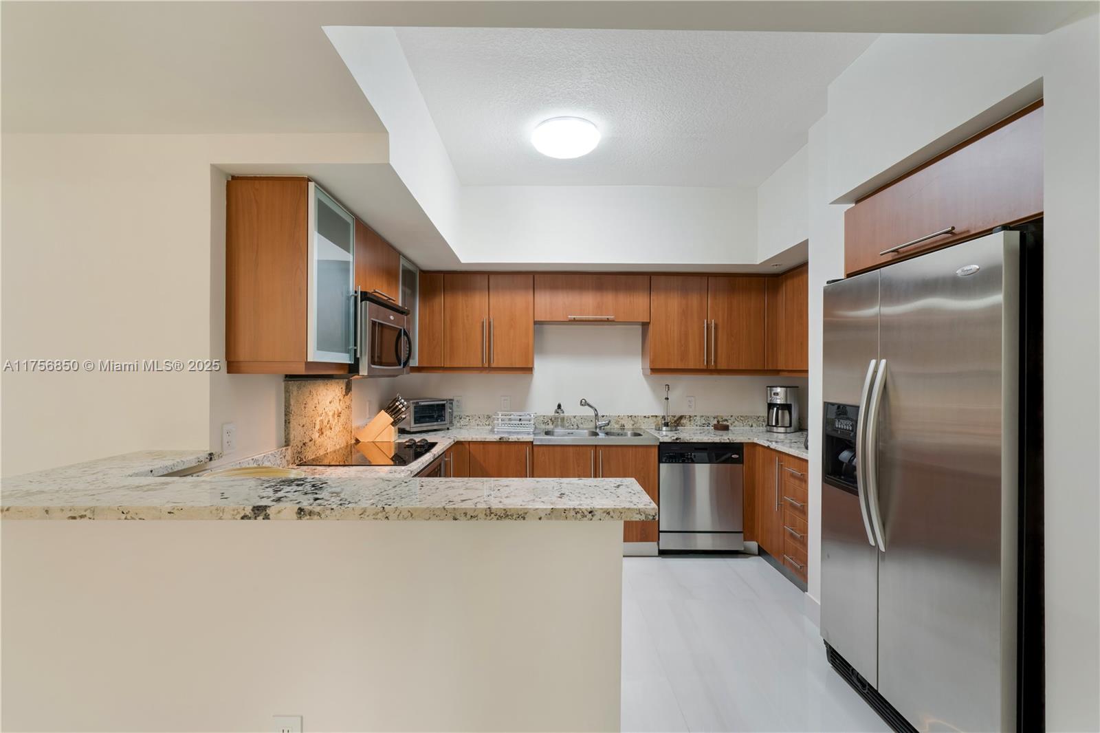 888 Douglas Road, Unit 404 Coral Gables, FL 33134 - Photo 4 of 21 a kitchen with stainless steel appliances granite countertop a refrigerator a stove and a sink with wooden floor