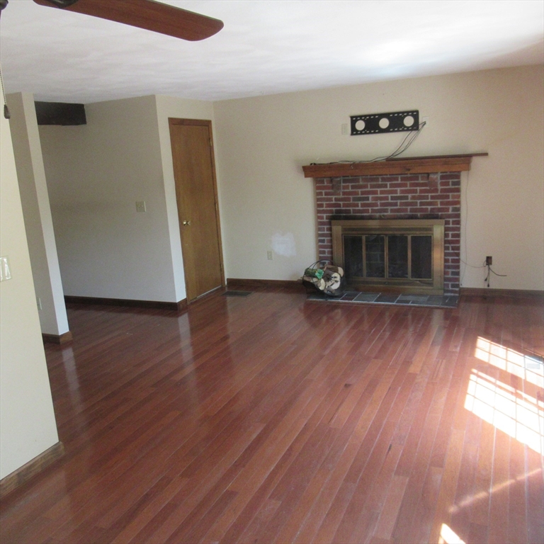 52 Apache Way, Unit 52 Tewksbury, MA 01876 - Photo 7 of 19 a view of an empty room with wooden floor and a fireplace