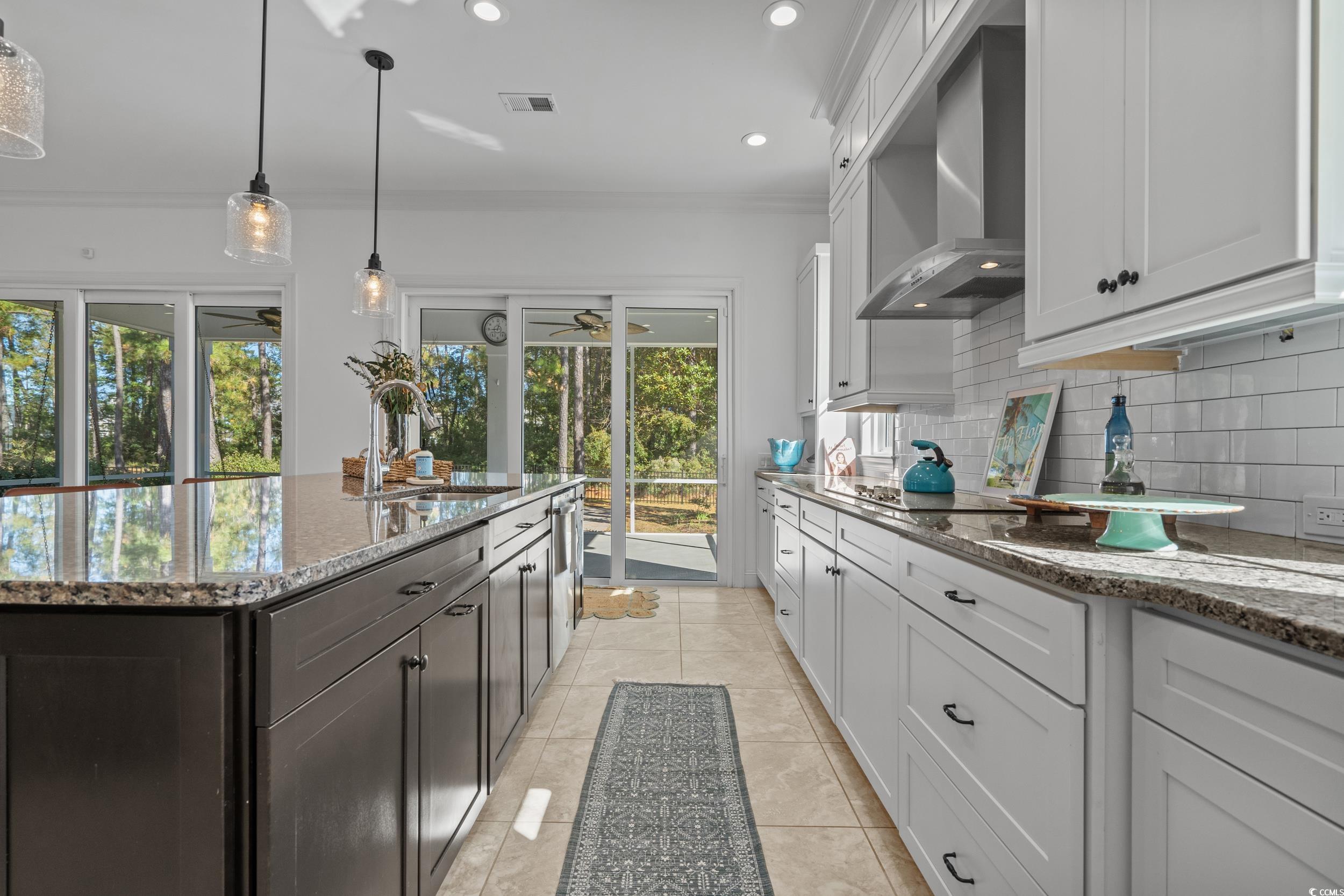 496 Starlit Way Myrtle Beach, SC 29579 - Photo 15 of 40 Kitchen featuring dark stone counters, wall chimney range hood, pendant lighting, recessed lighting, and white cabinets