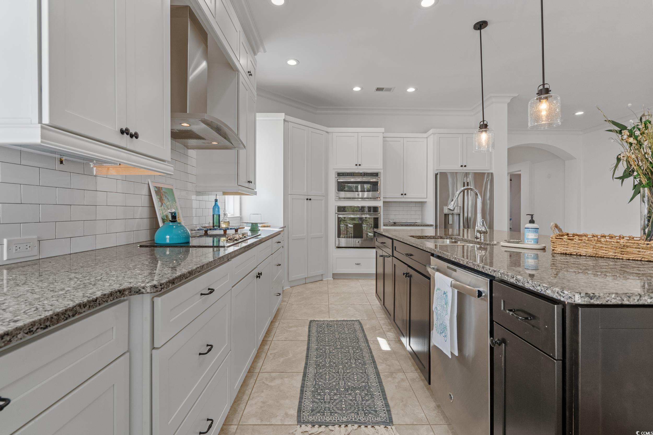 496 Starlit Way Myrtle Beach, SC 29579 - Photo 19 of 40 Kitchen with white cabinets, arched walkways, wall chimney exhaust hood, appliances with stainless steel finishes, and recessed lighting