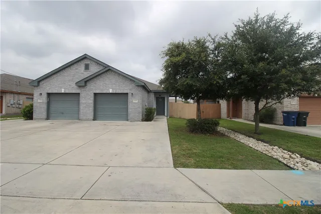 a view of a house with a yard and large tree