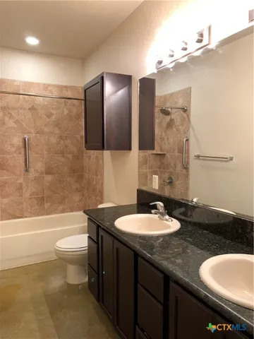 a bathroom with a granite countertop sink a toilet a mirror and bathtub
