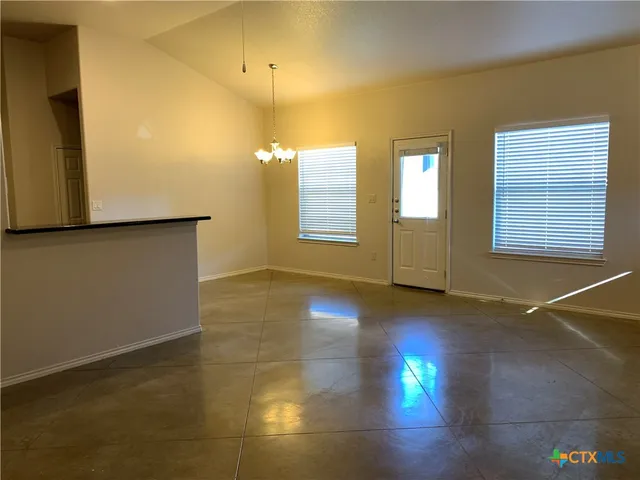 a view of an empty room with window and hardwood floor