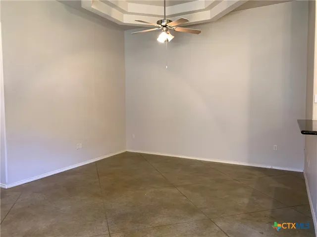 an empty room with a ceiling fan and carpet