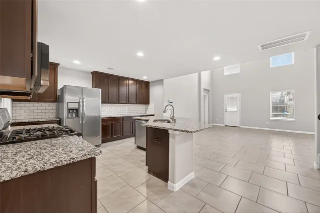 a kitchen with stainless steel appliances granite countertop a stove top oven a sink dishwasher a refrigerator and a microwave