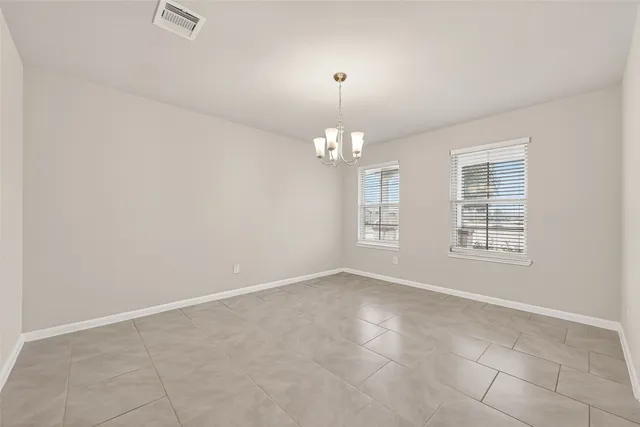 an empty room with chandelier fan and windows